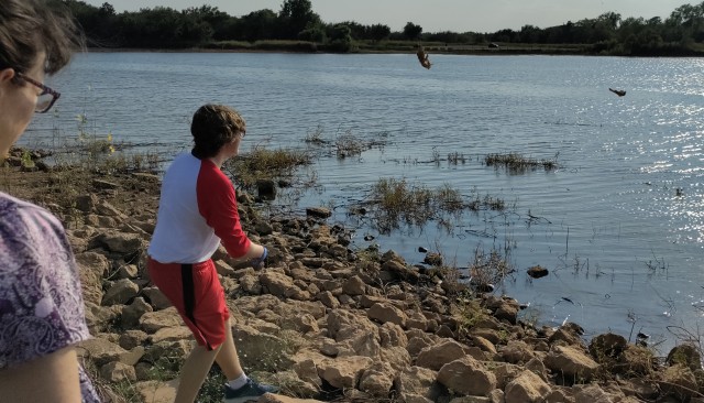 picture of teenage boy throwing fish heads into lake as part of a lake cleanup project at Lake Hefner