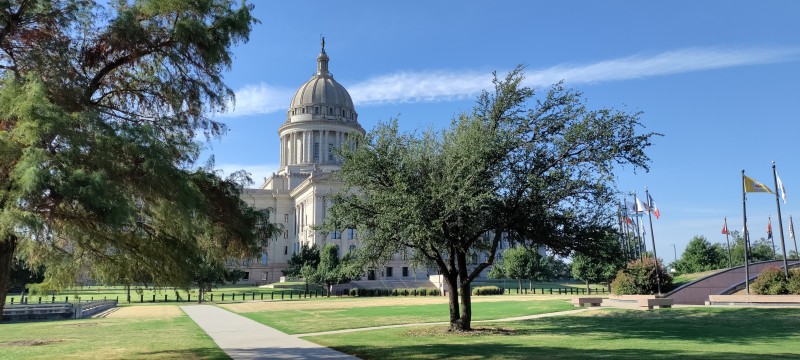 Oklahoma state capitol seen from the North, live oak trees in the foreground next to display of the flags of 39 Native American tribes of Oklahoma